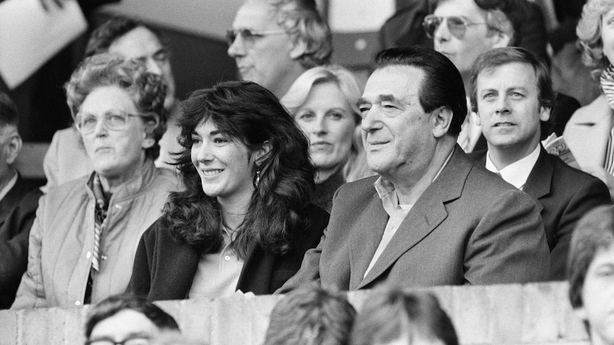 Ghislaine Maxwell sits and smiles next to her father, wearing a suit with dark hair,at a football match.