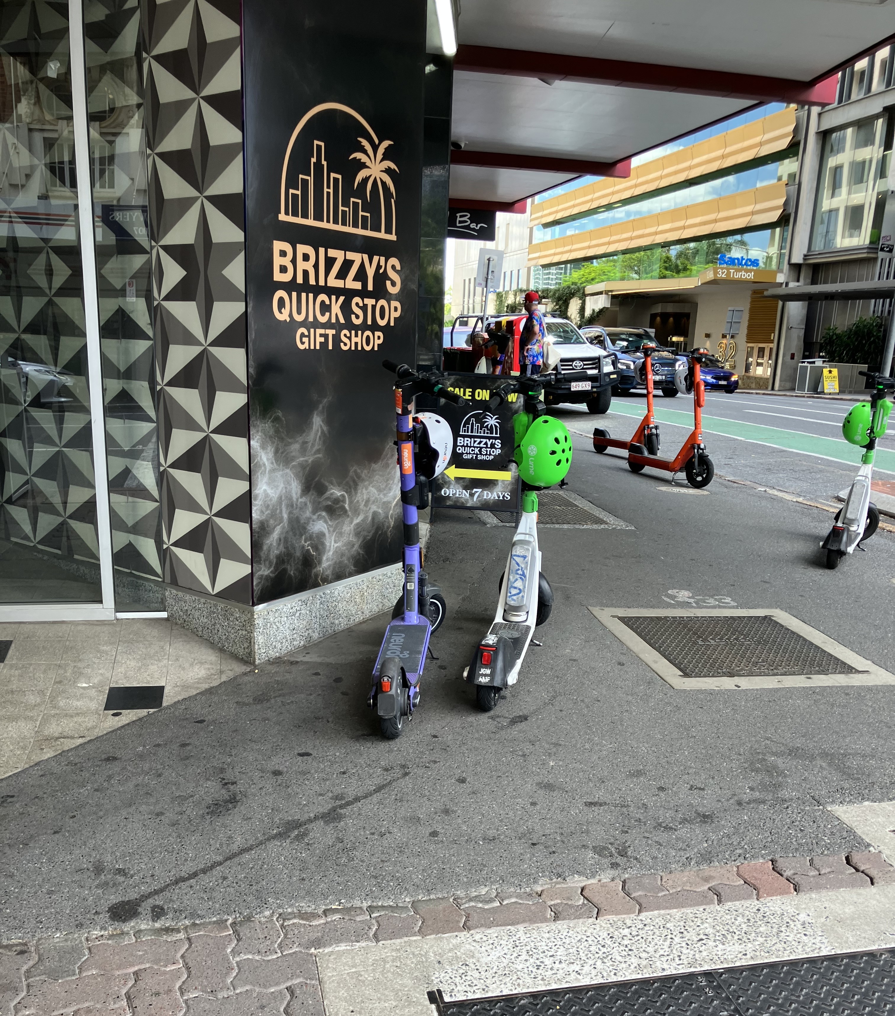 Duas scooters elétricas estacionadas em frente a uma loja no CBD de Brisbane
