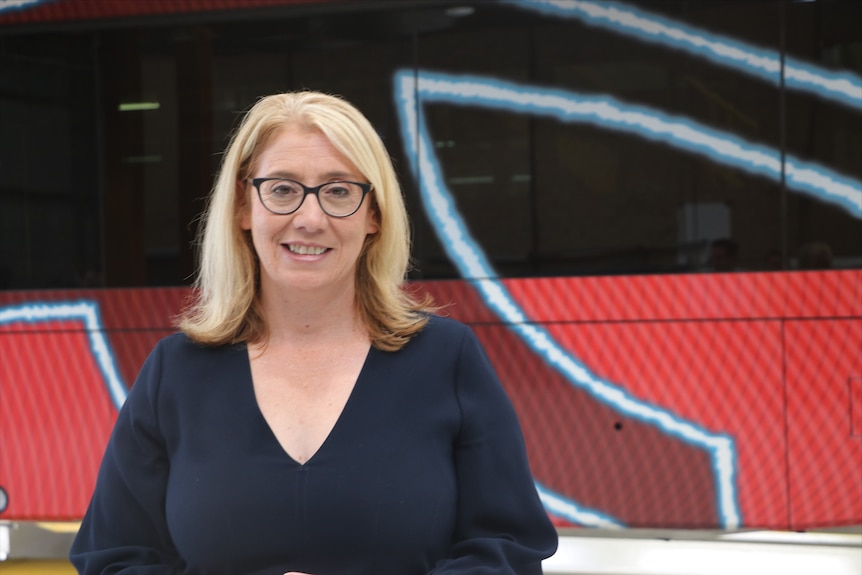 Mid-shot of Rita Saffioti looking at the camera with a red bus behind her