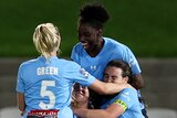Several Sydney A-League Women players embrace as they celebrate a goal.