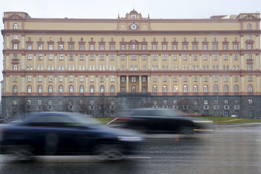 A large building in Russia with cars speeding past it 