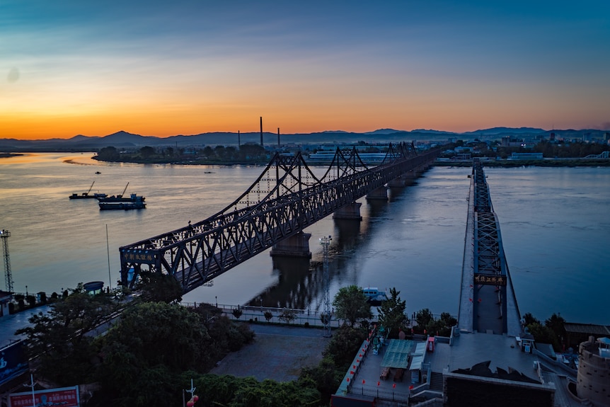 A view of the river and bridge in the Chinese port city of Dandong at sunset.