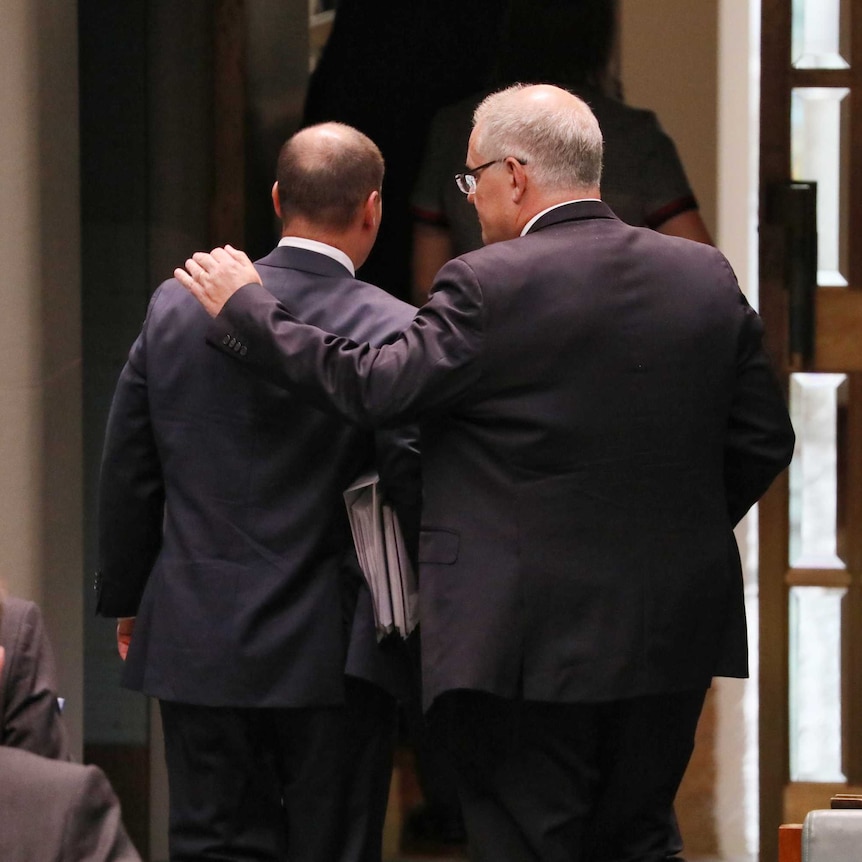 Prime Minister Scott Morrison is seen from behind putting his arm around Treasurer Josh Frydenberg as they leave Parliament.