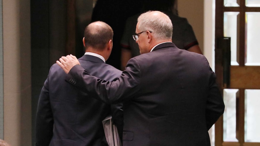 Prime Minister Scott Morrison is seen from behind putting his arm around Treasurer Josh Frydenberg as they leave Parliament.