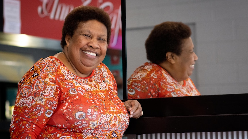 A woman wearing an orange top smiles at the camera