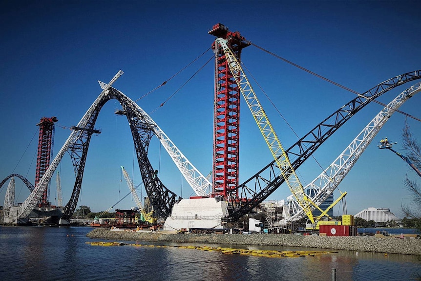 Matagarup Bridge near Perth Stadium under construction on a bright sunny day, with arches and towers stretching skywards.