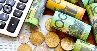 Rolled up bank notes and coins on a desk.