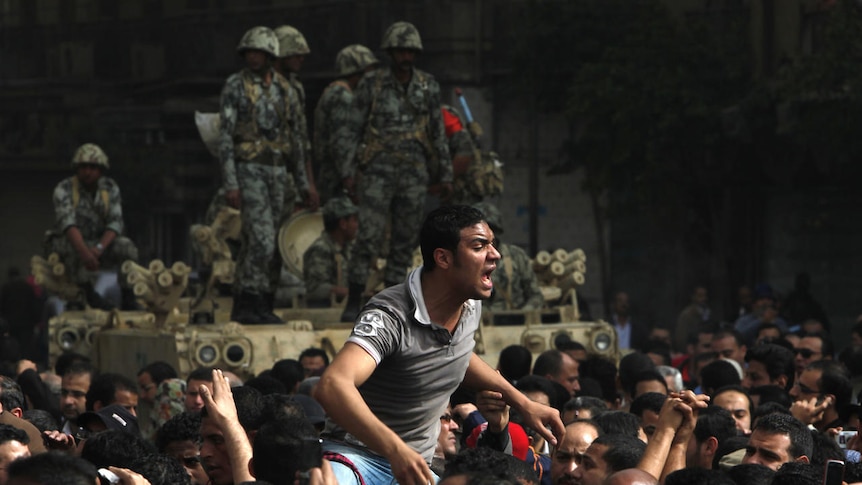 A protester on someone's shoulders yells during protests in Cairo