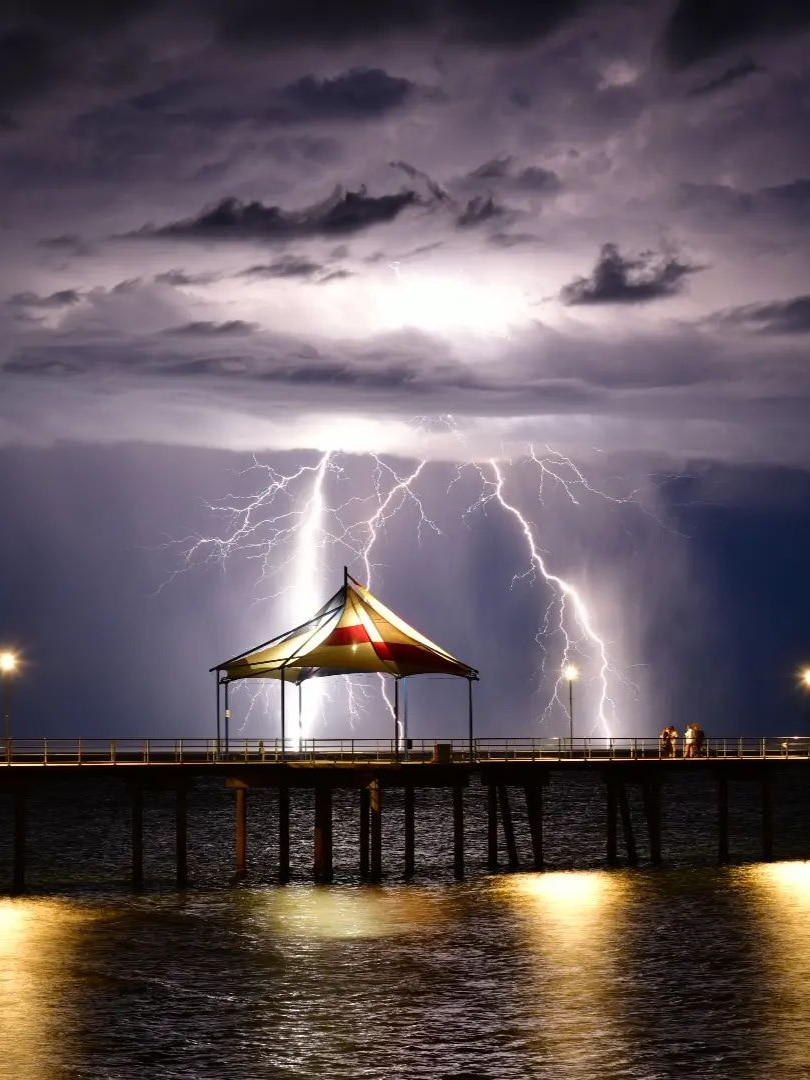 A lightning strike over a marquee on a jetty at a beach