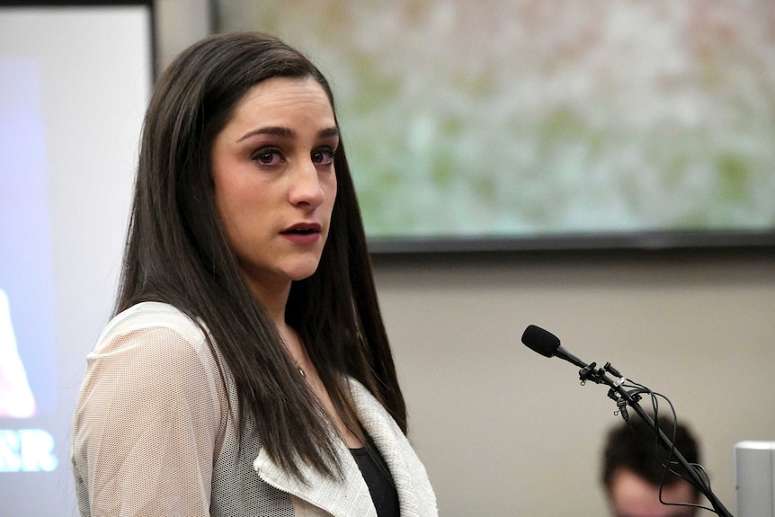 A young woman stands behind a microphone.