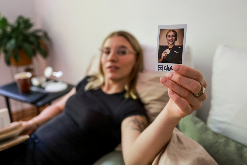 Marissa Williamson-Pohlman holding a photograph of themselves.