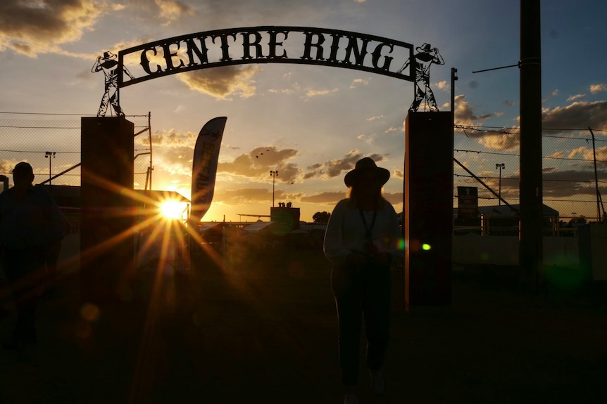 Sunset through centre ring at Beef Australia 2021, silhouette of a woman wearing a hat.