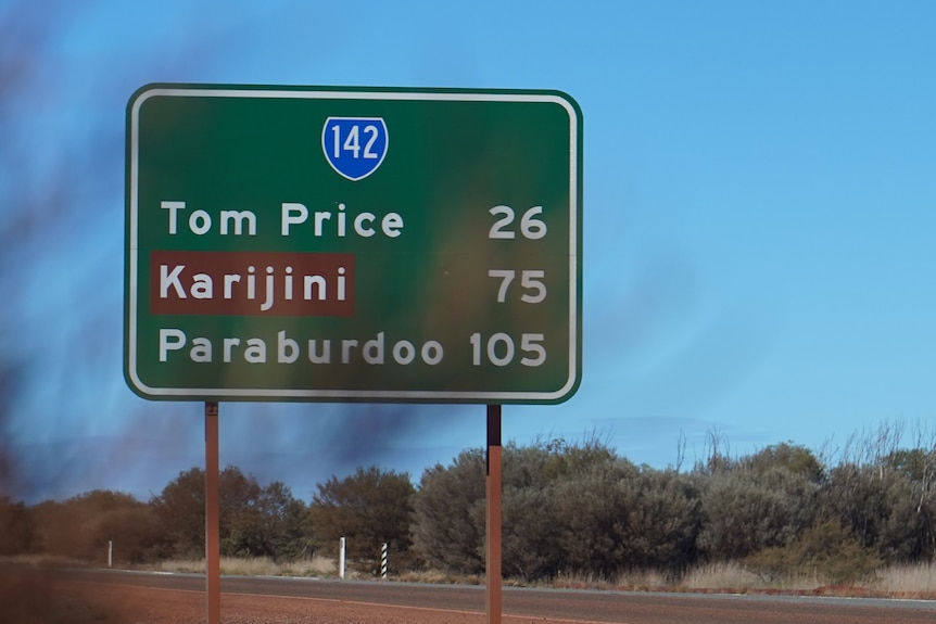 A green sign displaying distances to Tom Price Karijini and Paraburdoo