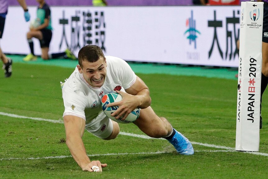 An England player dives across the goal line holding the ball to score a try against Australia at the Rugby World Cup.