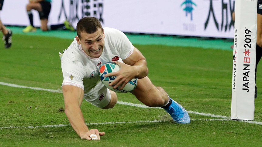 An England player dives across the goal line holding the ball to score a try against Australia at the Rugby World Cup.