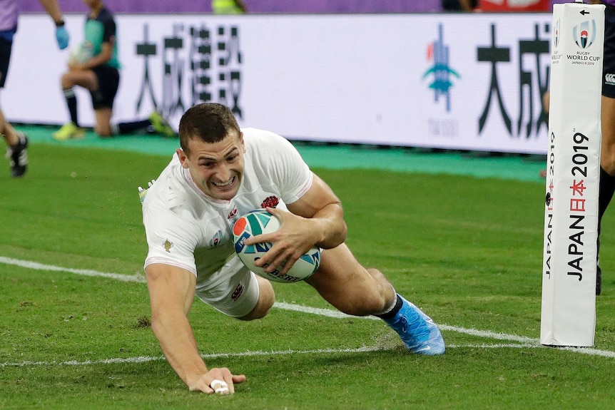 An England player dives across the goal line holding the ball to score a try against Australia at the Rugby World Cup.