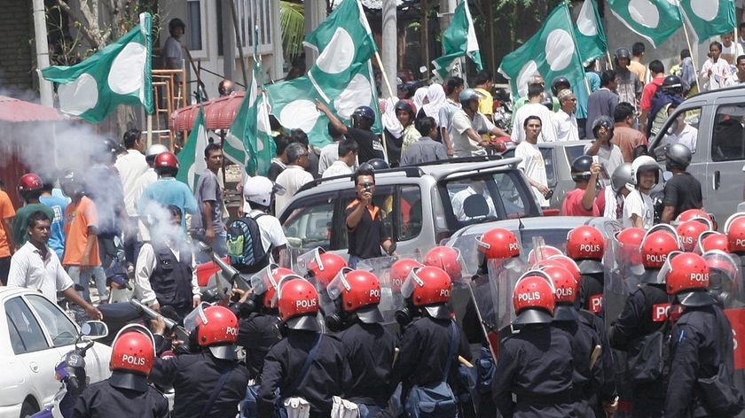 Riot police stand their ground as they fires tear gas into a crowd of opposition Pan-Malaysian Islamic Party (PAS) demonstrators.