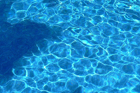 Water in a backyard pool shimmering in sunlight.