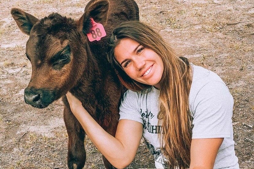 A young woman cuddles a brown calf