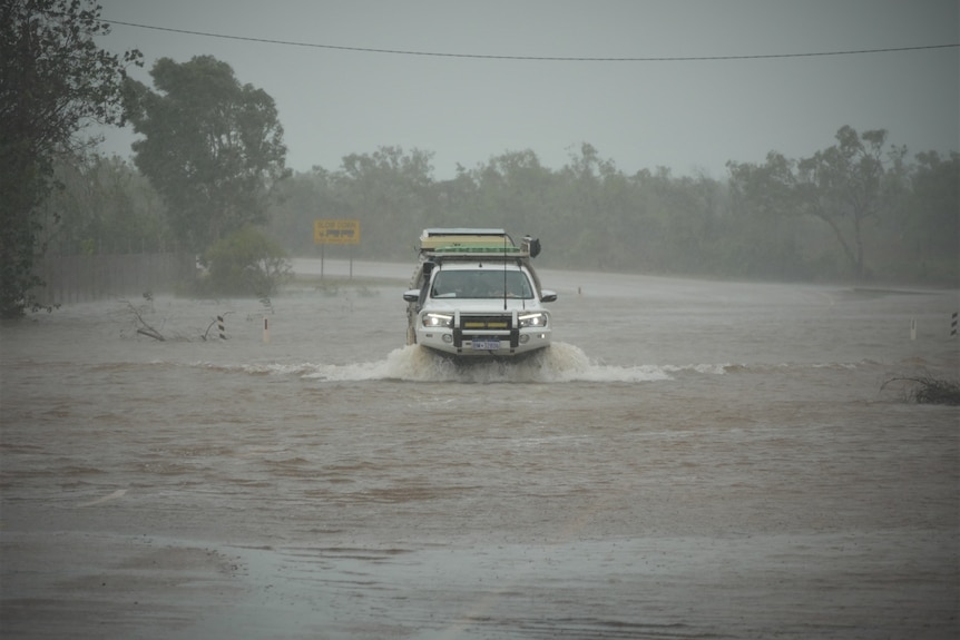 a 4WD drives through floodwater across a road