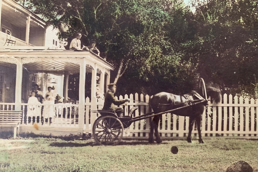Horse and jinker in front of a double-storey plantation house.