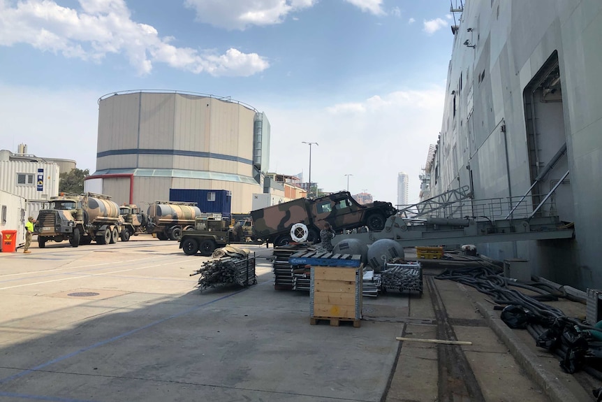 A convoy of trucks boarding a navy ship.