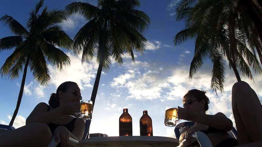 Two women toast with their fears in a tropical paradise under palm trees