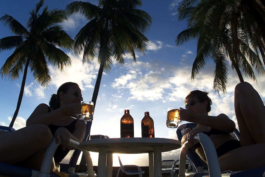 Two women are tormented in a tropical paradise under palm trees.