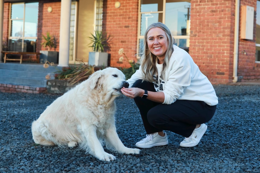 A young woman feeds a treat to her golden retriever dog