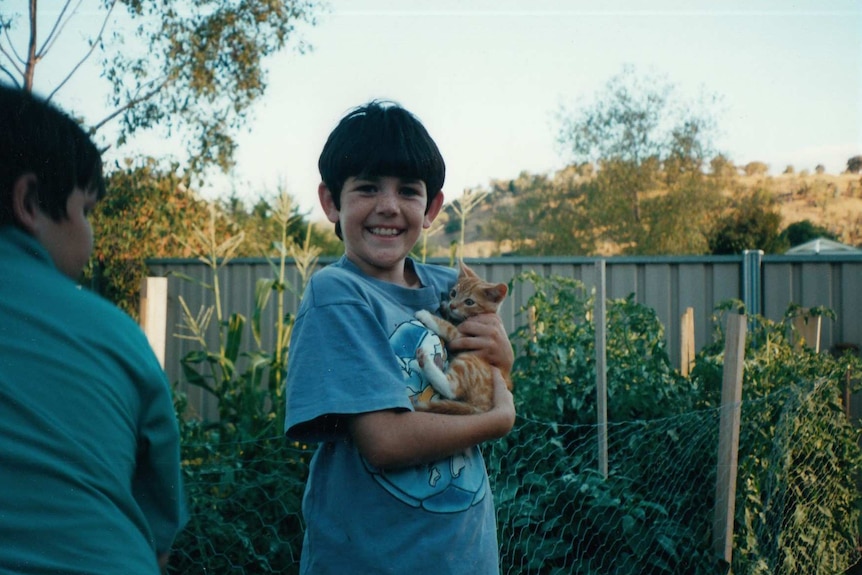 A photo of Ash Morris when he was a child, holding a cat.