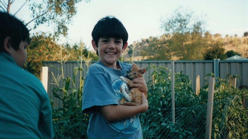 A photo of Ash Morris when he was a child, holding a cat.