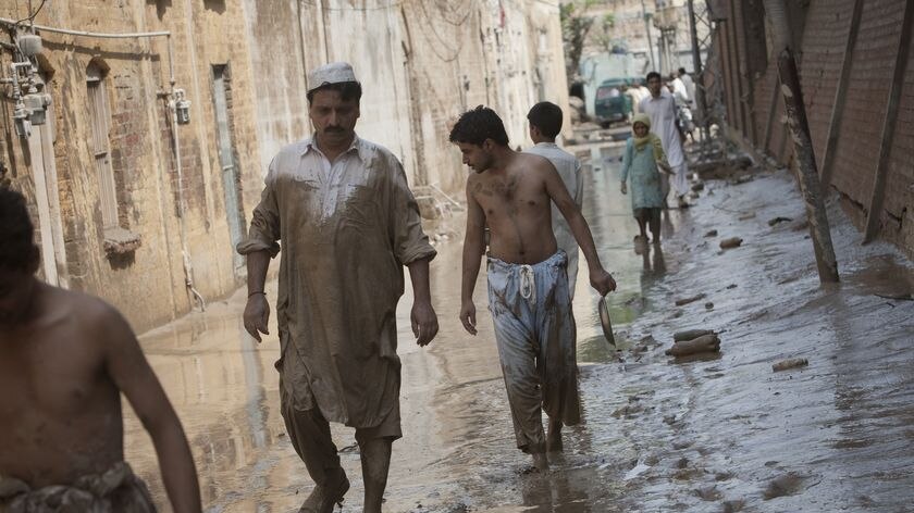 Pakistani residents wade through a flood-affected street