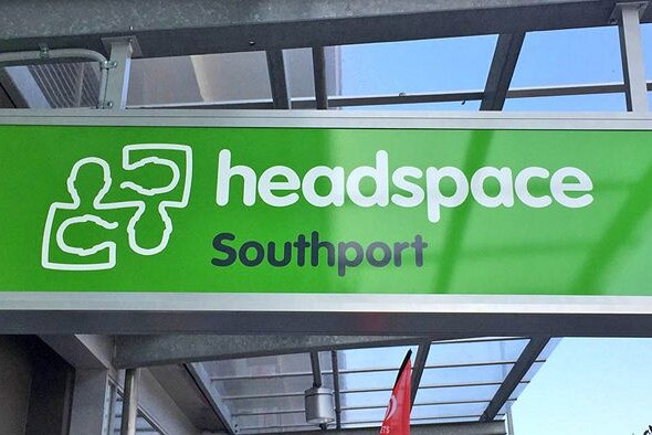 A sign under the awning of a building saying headspace in white writing on a green background