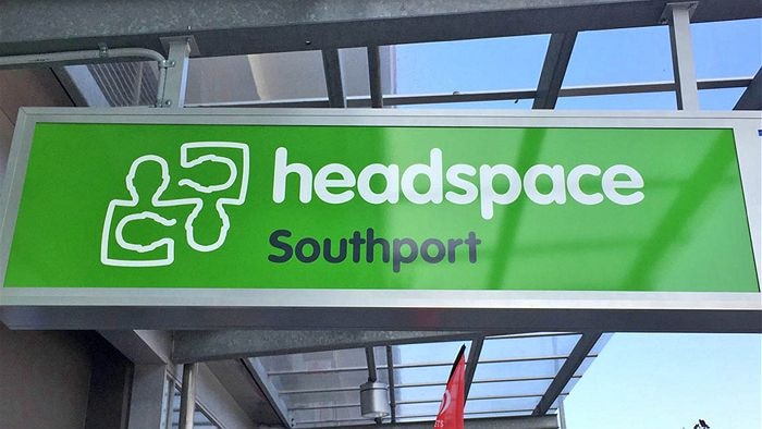 A sign under the awning of a building saying headspace in white writing on a green background