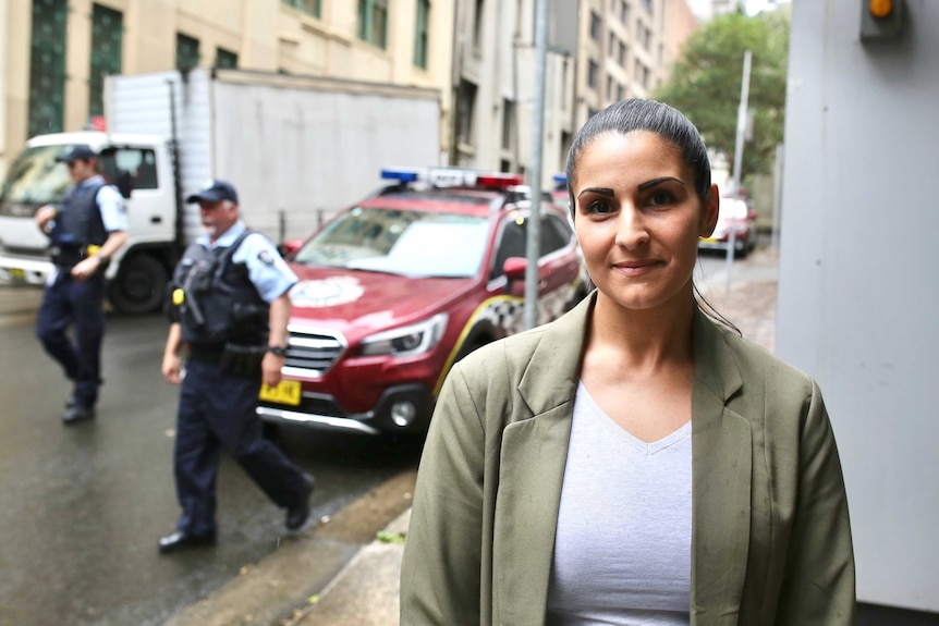 AFP Digital Forensic team member Jennifer Garcia stands in front of police cars and two AFP officers