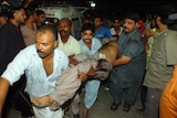 Volunteers at a Pakistani hospital shift a bomb blast victim