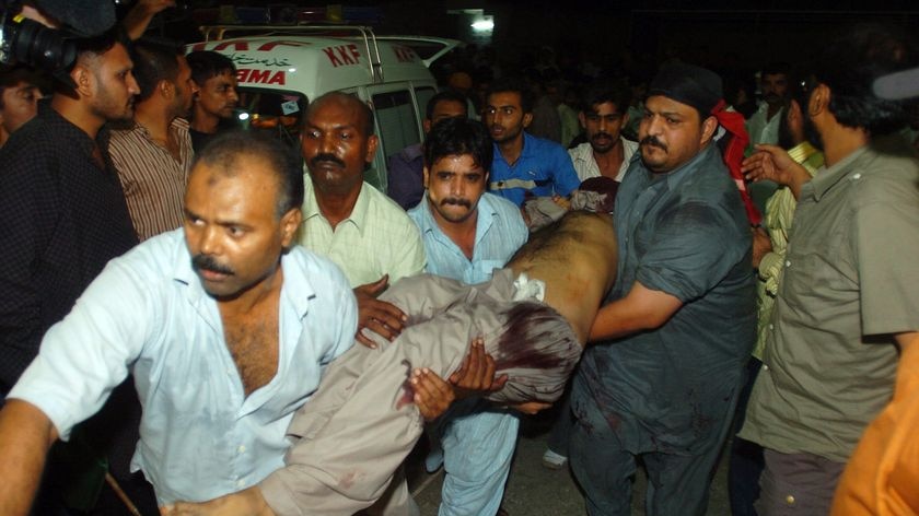 In the line of fire: Volunteers at a Pakistani hospital carry one of the bomb blast victims