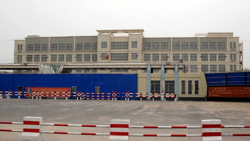 A wide shot of a big, dull-looking building with security fences around the outside.