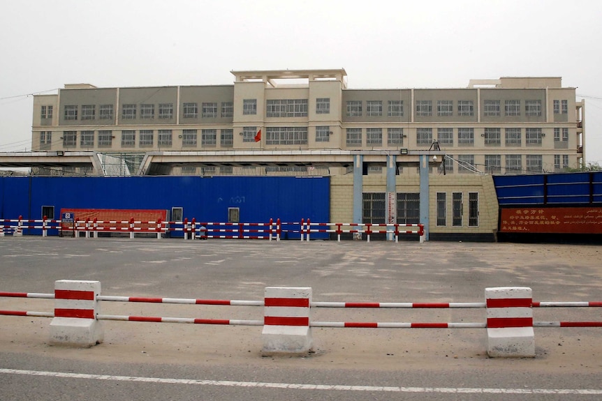 A wide shot of a big, dull-looking building with security fences around the outside.