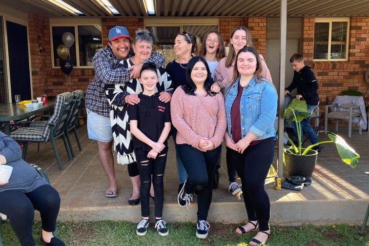 A group of family stand smiling.