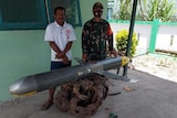 Two men, one in military uniform, stand with an underwater drone