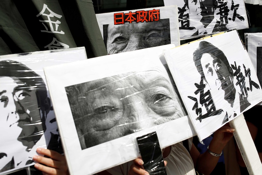 Protestors hold pictures of "comfort women" calling for an apology.
