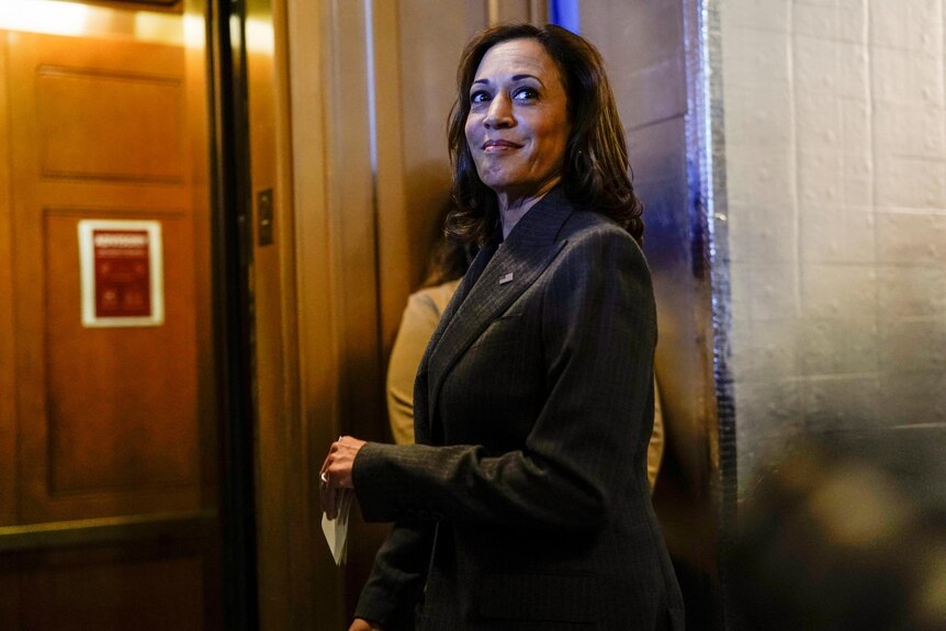 Kamala Harris standing and looking into the distance with a smile on her face.