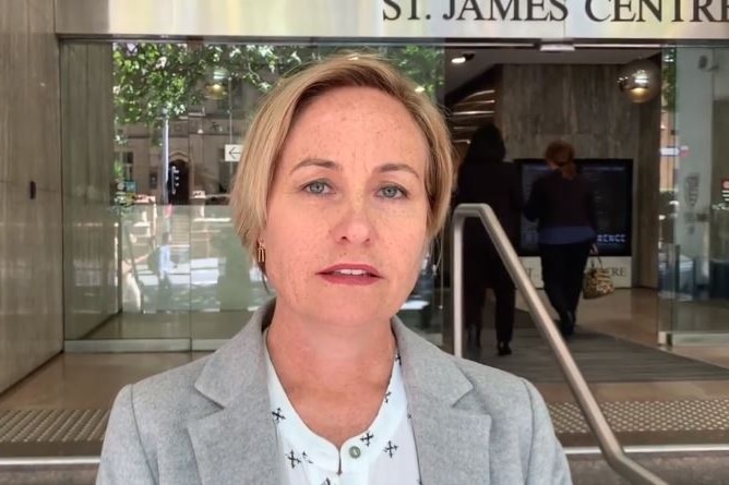 a woman standing outside a court room talking