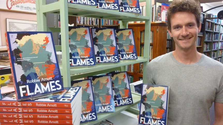 author standing beside a stack of his books