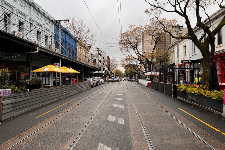 Shop fronts line Gertrude Street, viewed under cloudy grey skies.