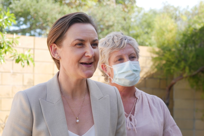 A woman speaks in front of a second woman