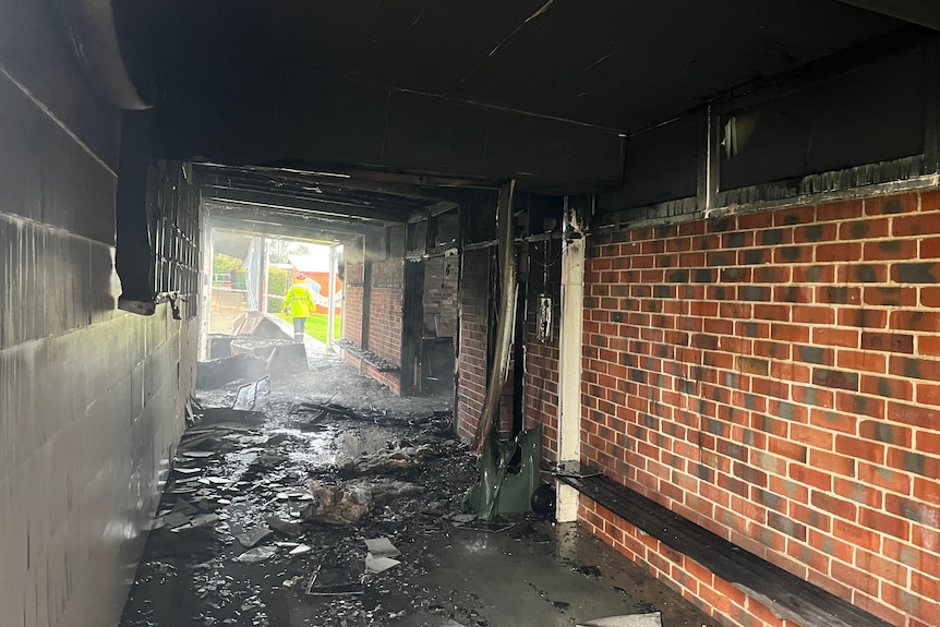 A long hallway with black roof and signs of burnt items on the floor