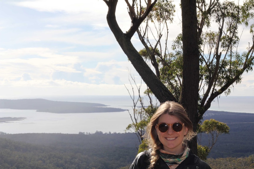 Picture of a woman wearing sunglasses overlooking the coast.