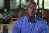Michael Jordan wears a blue polo shirt seated in interview chair